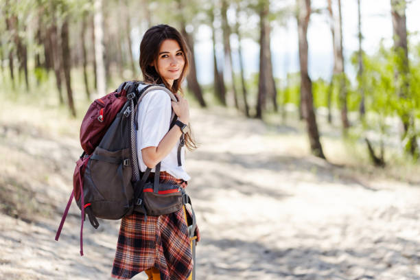 istock Positive woman with backpack and knit shirt looking at camera while hiking in forest 2160749821