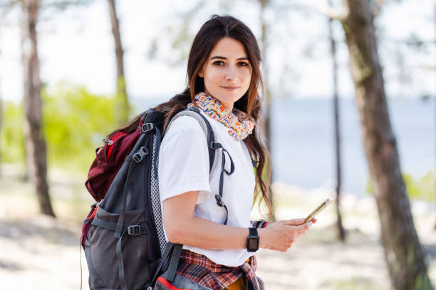 istock Attractive woman using smartphone and looking at camera in summer forest 2160749829