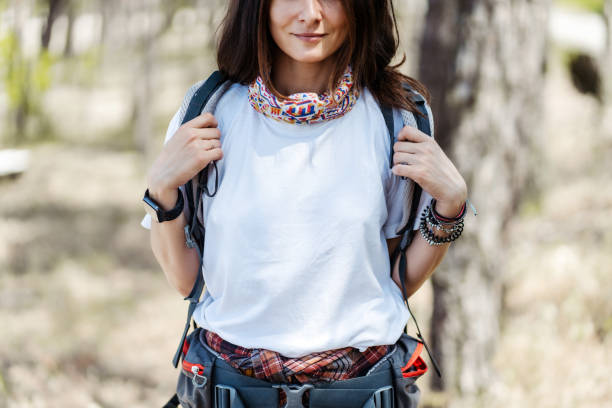 Closeup woman hiker with backpack looking at camera while hiking in forest
