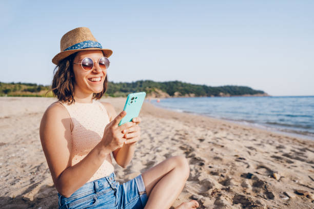 istock Woman using smart phone on the beach 2160750088