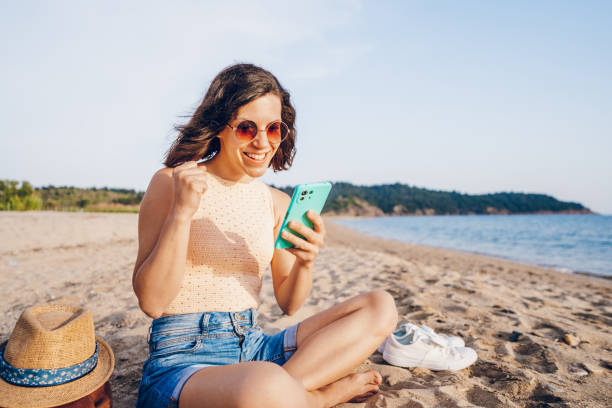 istock Woman using smart phone on the beach 2160750114