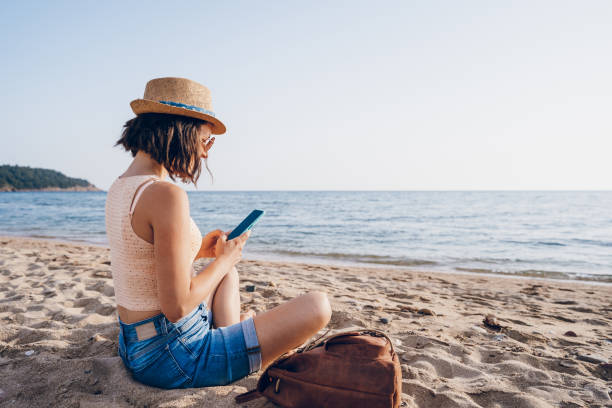 istock Woman using smart phone on the beach 2160750130