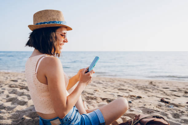 istock Woman using smart phone on the beach 2160750167