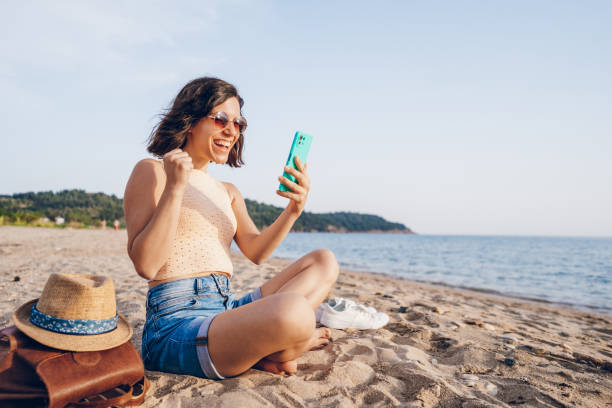 istock Woman using smart phone on the beach 2160750264