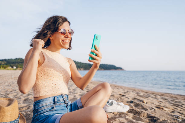 istock Woman using smart phone on the beach 2160750344