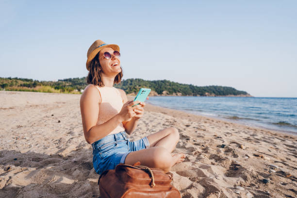 istock Woman using smart phone on the beach 2160750449