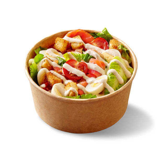 Caesar salad with lettuce, tomatoes, quail eggs, croutons and smoked salmon in cardboard bowl on white stok fotoğrafı