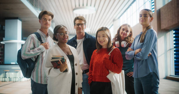 Diverse Group of Students Standing Together in Modern University Hallway. Multiethnic Young Adults with Books and Backpacks, Smiling and Posing for a Group Photo in a Brightly Lit Educational Setting