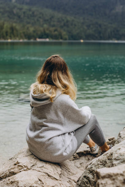 istock Young woman sitting on a mountain lake 2160752608