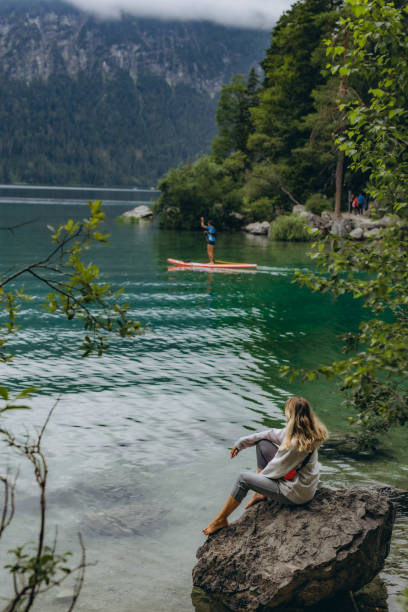 istock Young woman sitting on a mountain lake 2160752766