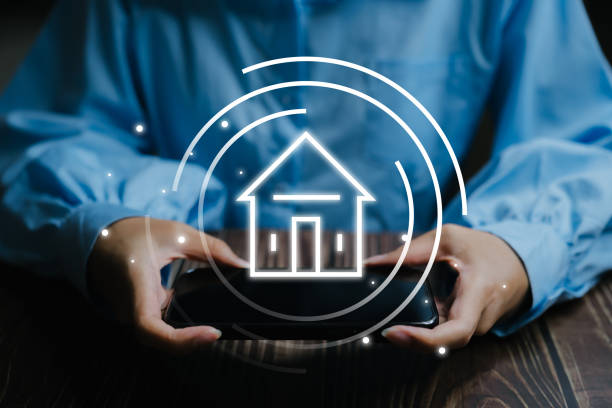 istock Person holding a smartphone with a smart home icon overlay, representing modern home automation and technology connectivity. 2160752847