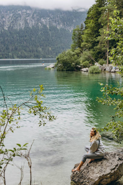 istock Young woman sitting on a mountain lake 2160754391