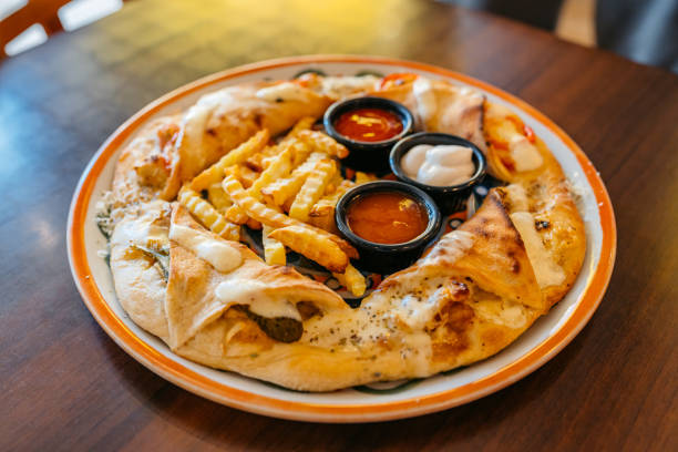Ring shaped stuffed pastry (Italian crescent ring) served with dipping sauces and fries in a pub.