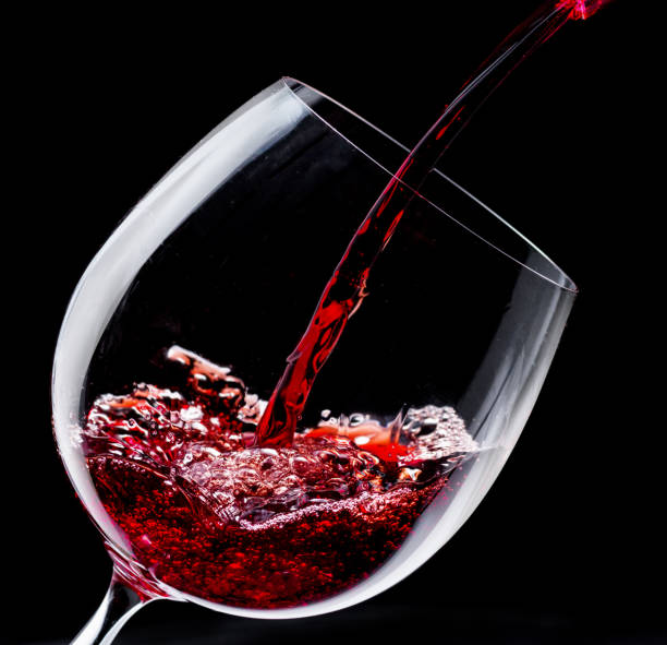istock Pouring red wine into a wine glass at the black background. 2160773143