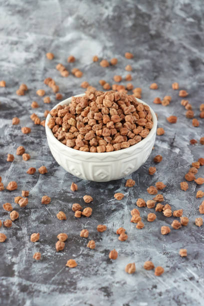 istock Image of dried bengal gram black chickpeas in white ceramic bowl, surrounded by scattered lentils and pulses, healthy food, pulses, lentils, against granite kitchen worktop background 2160773837
