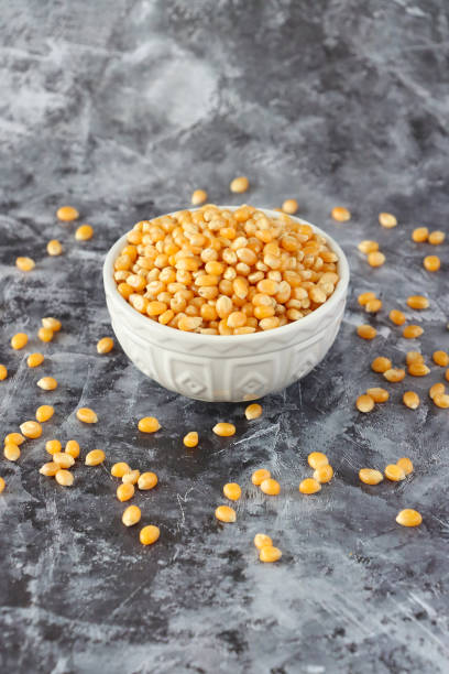 istock Image of dried popping corn kernels in white ceramic bowl, surrounded by scattered seeds, nuts and pulses, healthy food, corns, lentils, against granite kitchen worktop background 2160775527