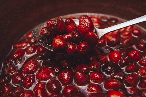 Red strawberry jam background. Homemade strawberry jam in making progress, boiling. Cooking fresh ripe berries for canning. Organic sweets, dessert.