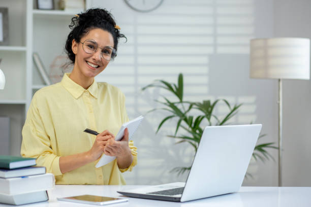 istock Smiling woman taking notes while working from home office with laptop 2160780782