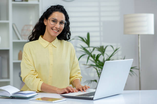 istock Smiling woman working on a laptop in a bright office with plants 2160781485