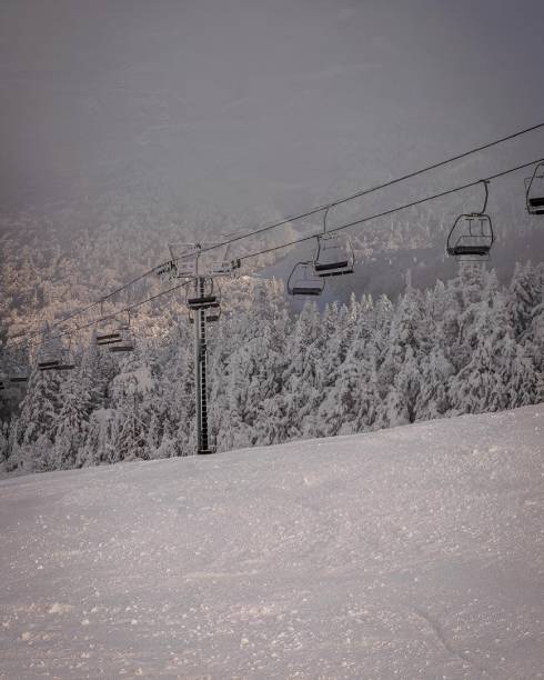 A serene winter landscape in Vermont featuring a ski lift over a snow-covered mountain with a forest in the background.