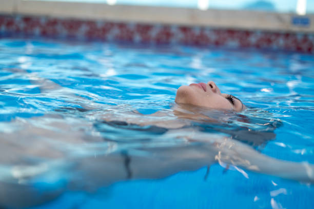 Young woman floating in the pool while enjoying her summer vacation