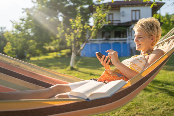 Vertical photo with copy space of a overweight Woman reading a book lying on an hammock in the forest