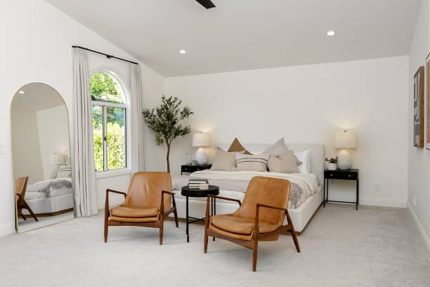 istock Modern bedroom interior with leather chairs, large mirror, and natural light from an arched window. 2160789113