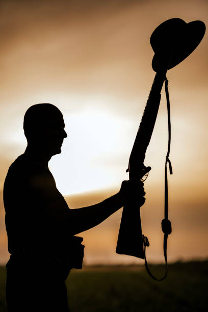 istock Hunter silhouette holding rifle and hat at sunset 2160792905
