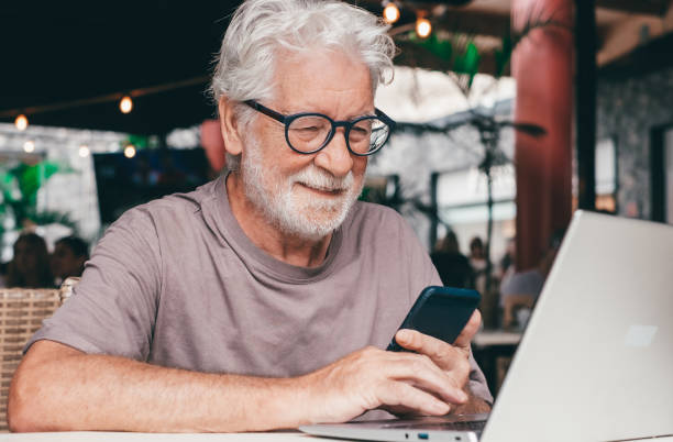 istock Attractive senior man sitting in a cafe smiling while using mobile phone. Cheerful senior male, using modern technology expressing happiness and contentment in a relaxed atmosphere 2160793116