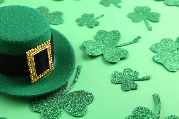istock St. Patrick's day. Leprechaun hat and decorative clover leaves on green background 2160796961