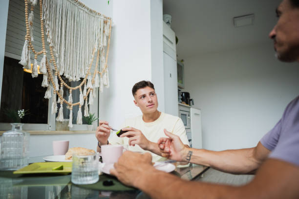 istock Young man eating avocado toast explaining something to friend during breakfast at home 2160802358