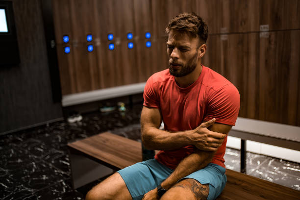 istock Tired athletic man having arm injury in locker room. 2160807116