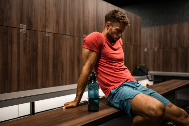 istock Tired athletic man resting in locker room. 2160807296