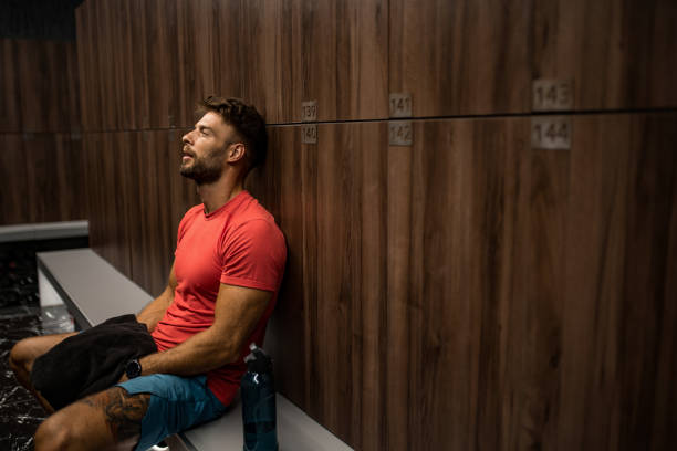 istock Tired athletic man resting in locker room. 2160807741