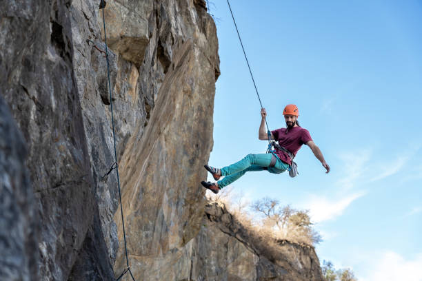 Young man climbing a challenging route on a cliff with a rope.