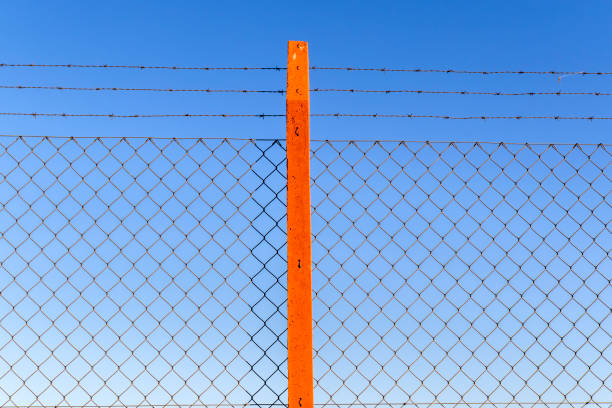 Mesh fence and barbed wire separated by concrete stake and with the blue sky in the background in Brazil