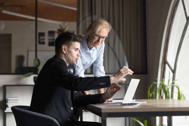 istock Two younger and elder business professionals discussing project tasks 2160821440