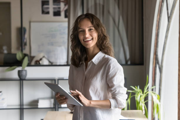 istock Happy attractive young manager woman holding tablet, using online application 2160821653