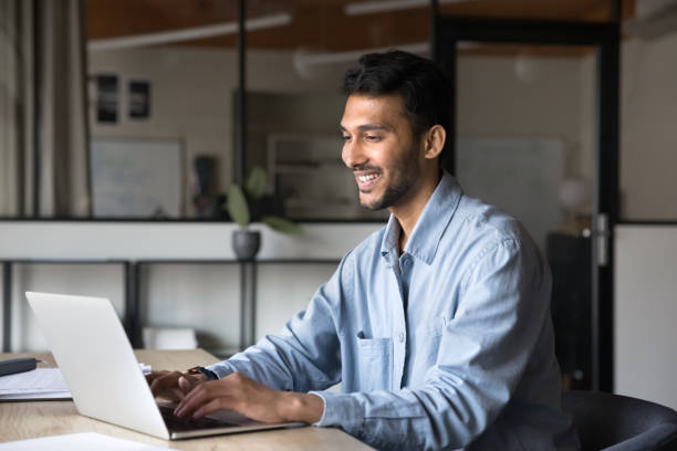 istock Cheerful young Indian entrepreneur man typing on laptop 2160821675