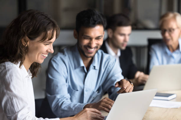 istock Cheerful multiethnic coworkers talking and laughing at laptop 2160822905