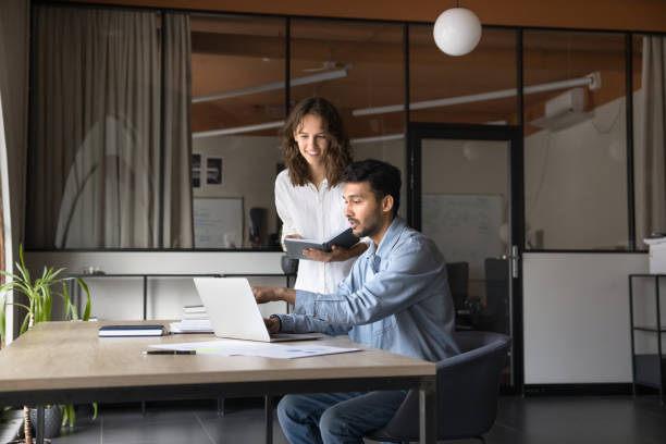 istock Two positive diverse business colleagues working on project at laptop 2160824773