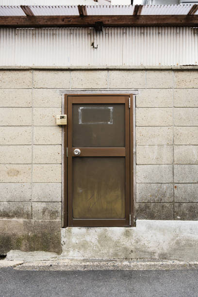 Close-up on a small old brown door in a dirty concrete wall.