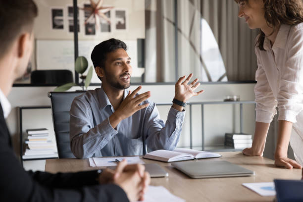 istock Positive inspired young Indian boss man talking to work colleagues 2160828242
