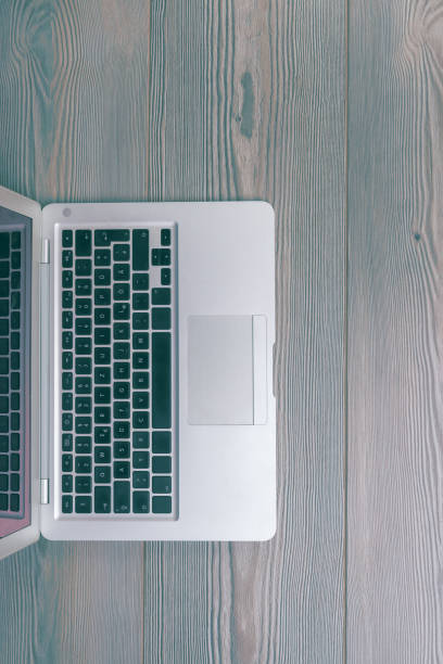 Sleek silver laptop on a vintage wooden desk with copy space, perfect for adding modern tech to your workspace