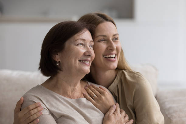 istock Two-generational women hugging sit on sofa staring into distance 2160836902