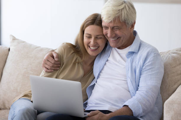 istock Retired man and daughter relaxing on couch with laptop 2160837983