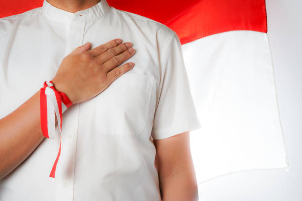 man's hand on chest, with indonesian flag background, independence day
