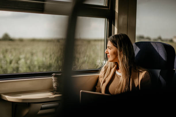 young woman travels by train, using lap top and looking out the window