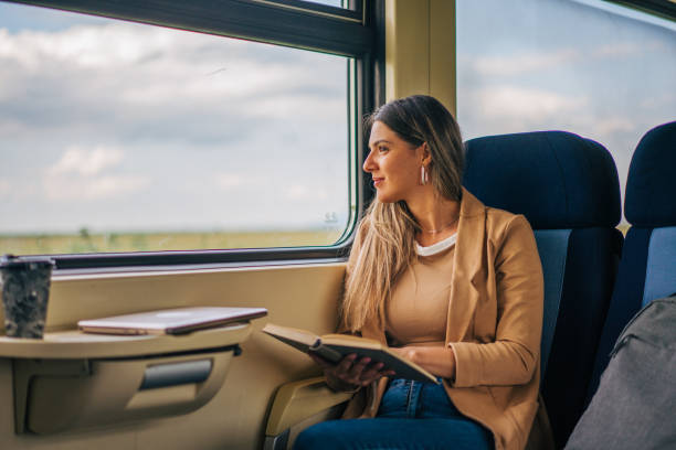 istock young woman travels by train, reading book 2160845298