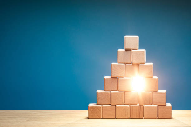 A wooden block pyramid with a single block missing, and a bright light shines through the gap. Vacant place in the team concept